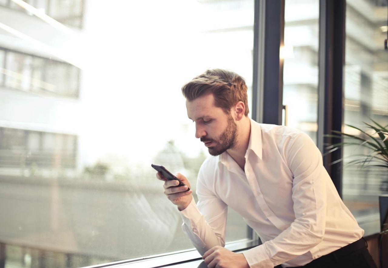 A smiling man in a shirt using a mobile phone in an office